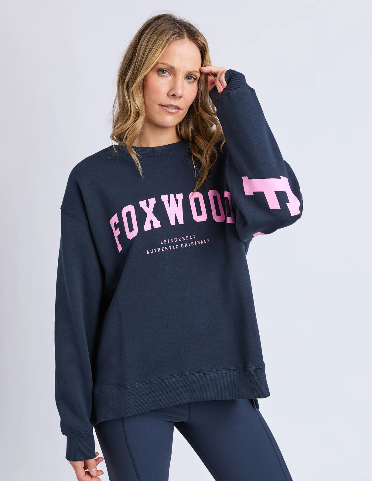 Woman wearing a navy sweatshirt with pink text on a white background